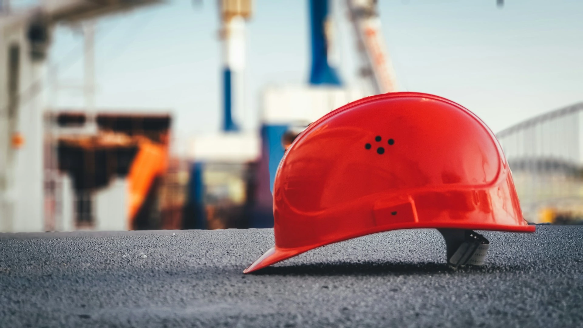 Casque de chantier rouge posé sur le sol d'un site de construction.